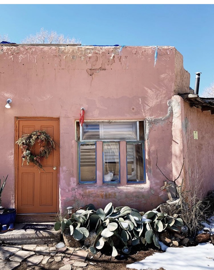 pink adobe house with a wooden door and cactus